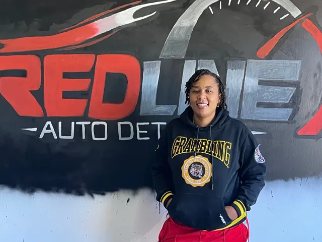 Visitor standing beside the Redline Auto Detailing wall logo