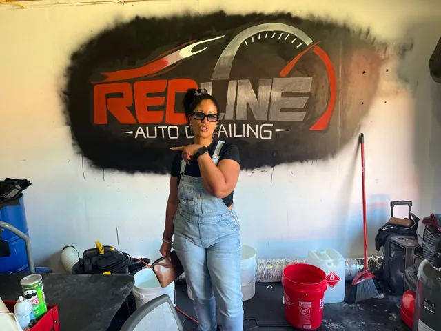 Visitor beside the Redline Auto Detailing logo inside the shop